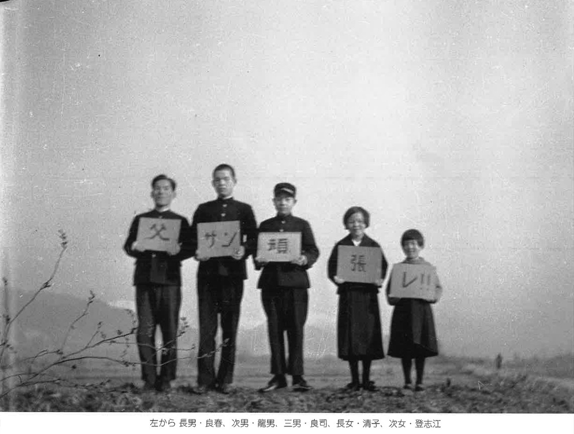 一文字ずつ板を掲げた五人兄妹の写真